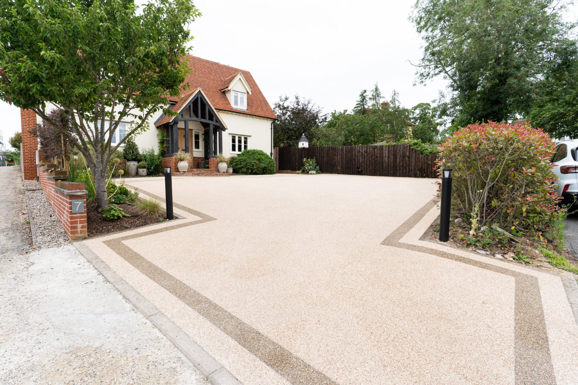 Aerial drone footage orbiting a luxury resin-bound driveway in front of a country cottage